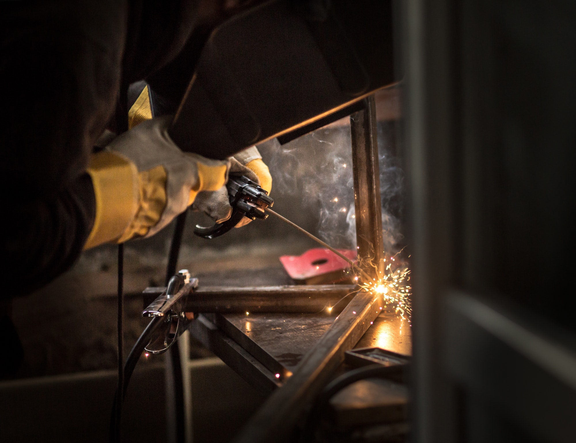 a man with a welding machine welds a metal structure, sparks fly.